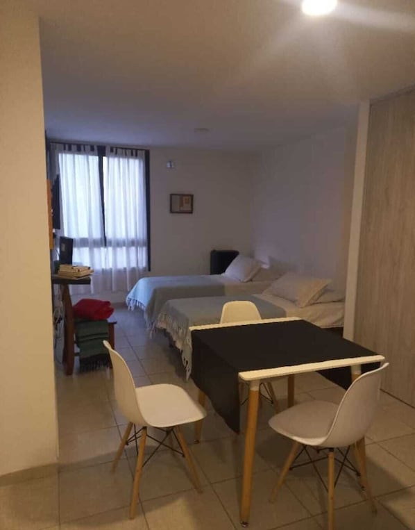 A room with a bed, a desk, and a dining table with chairs.