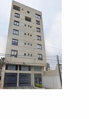 A multi-story building with a flat facade, several windows, and a garage entrance.