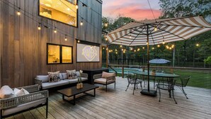 Une terrasse dotée de mobilier d’extérieur, d’une piscine et d’un grand parasol.
