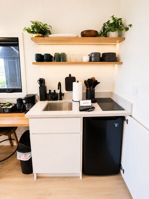 Una cocina compacta con lavavajillas integrado, cafetera y un pequeño cubo de basura.
