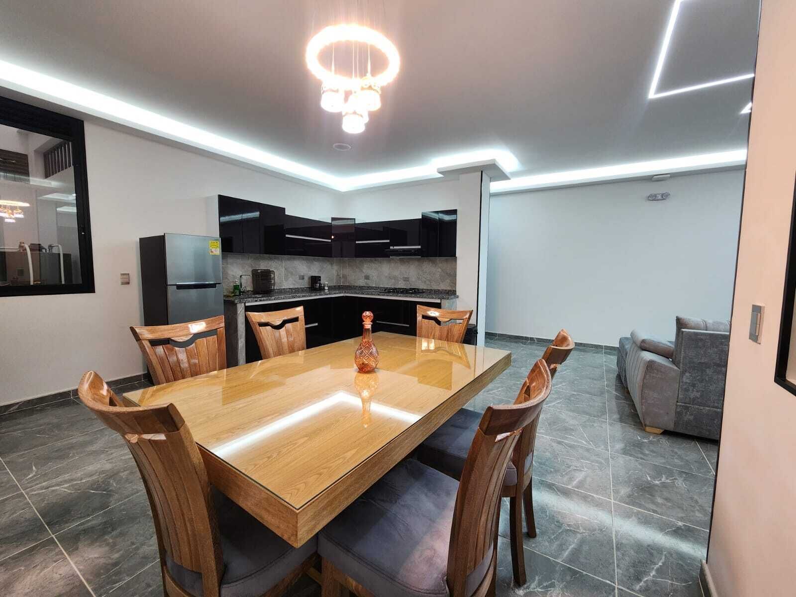 A modern kitchen with dark cabinets, a built-in oven, and a refrigerator.