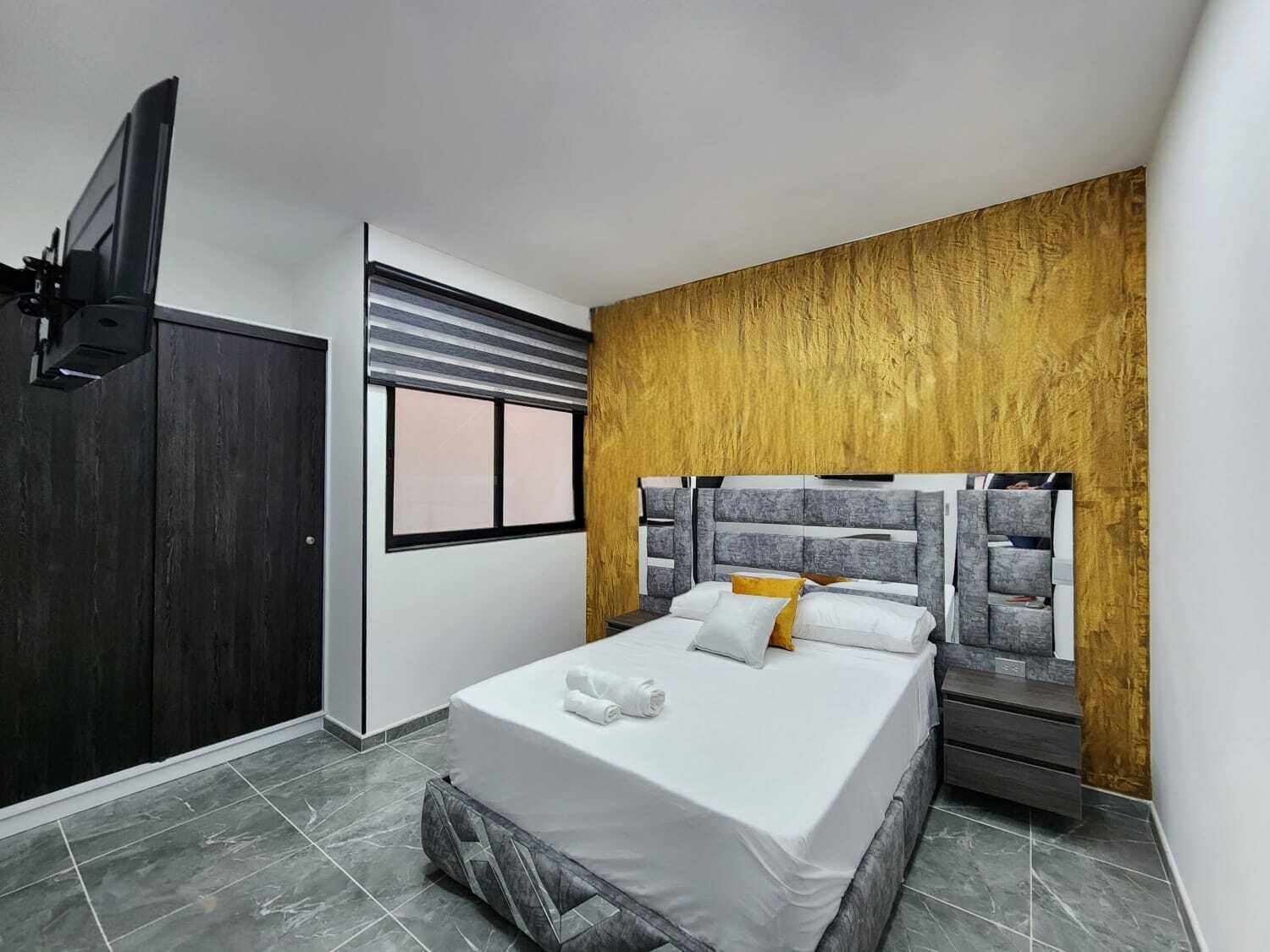A modern bedroom with a bed, a TV, a wardrobe, and a window.