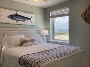 A bedroom with a bed, a window with a view, a lamp, and a wall art of a fish. - Beautiful gulf front 2 bedroom 2 bath steps to the water (Gulf Shores)