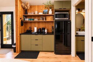 Eine moderne Küche mit Holzelementen, einem Edelstahl-Kühlschrank und einer Mikrowelle.