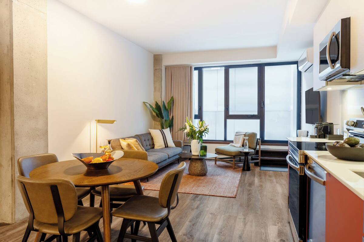 A modern living room with a dining area, a sofa, a coffee table, and a kitchen area with a microwave and oven.