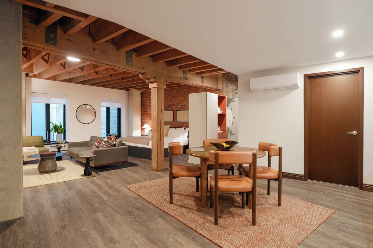 A spacious living area with a dining table, chairs, sofas, and a kitchen in the background.