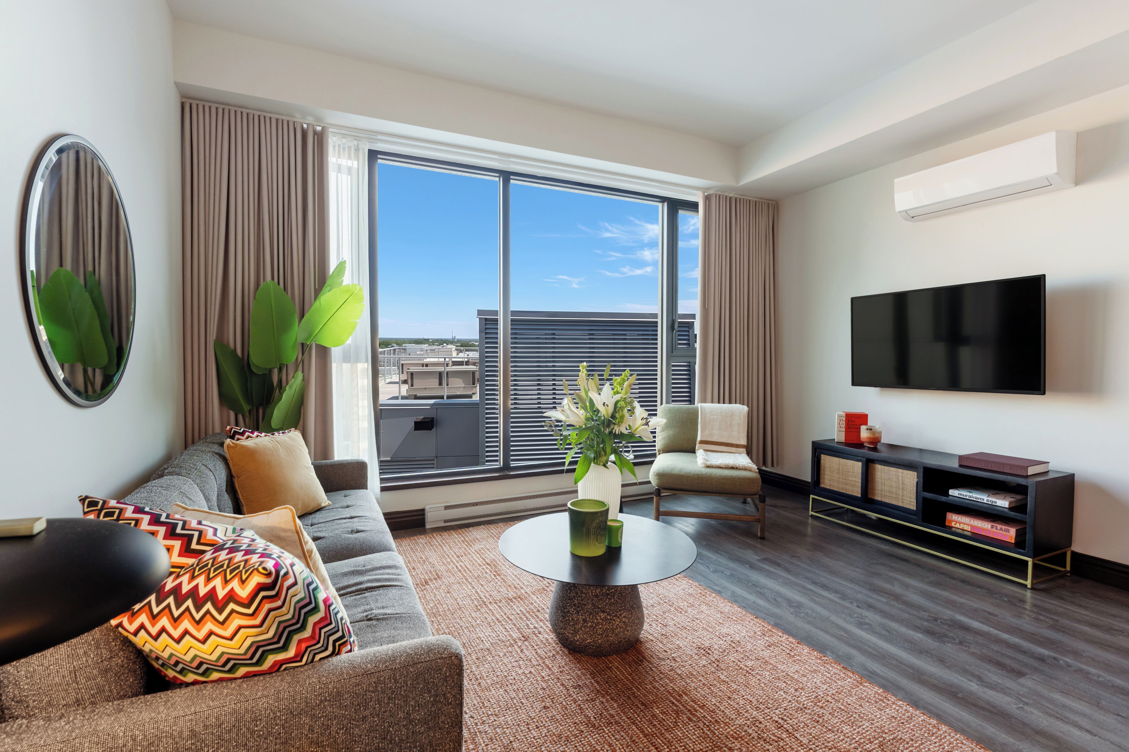 A modern living room with a sofa, armchair, coffee table, and a flat-screen TV.
