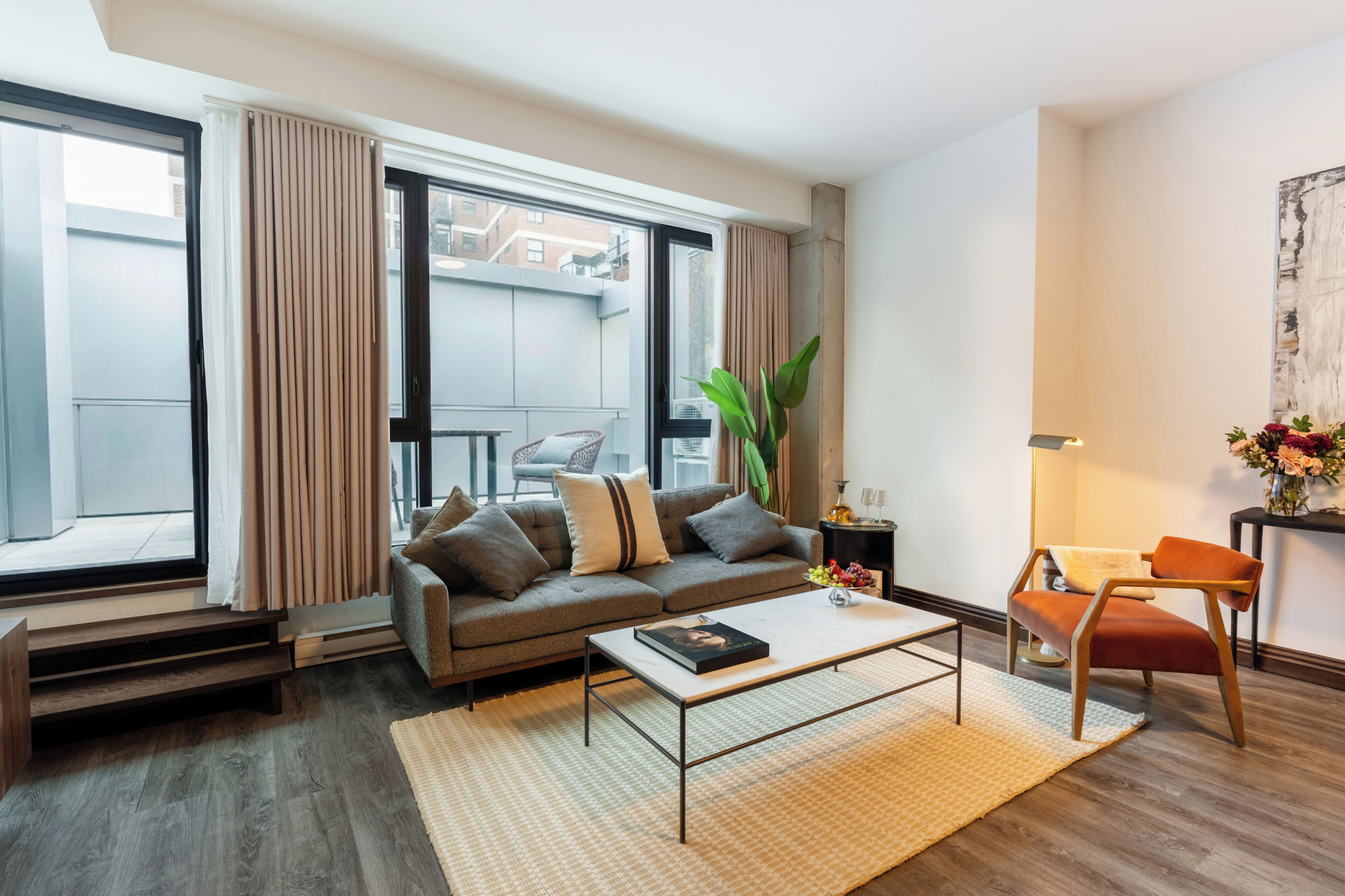 A modern living room with a sofa, coffee table, and a view of the outside.