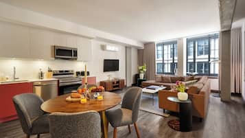 Una sala de estar moderna con comedor, cocina y ventanas amplias.
