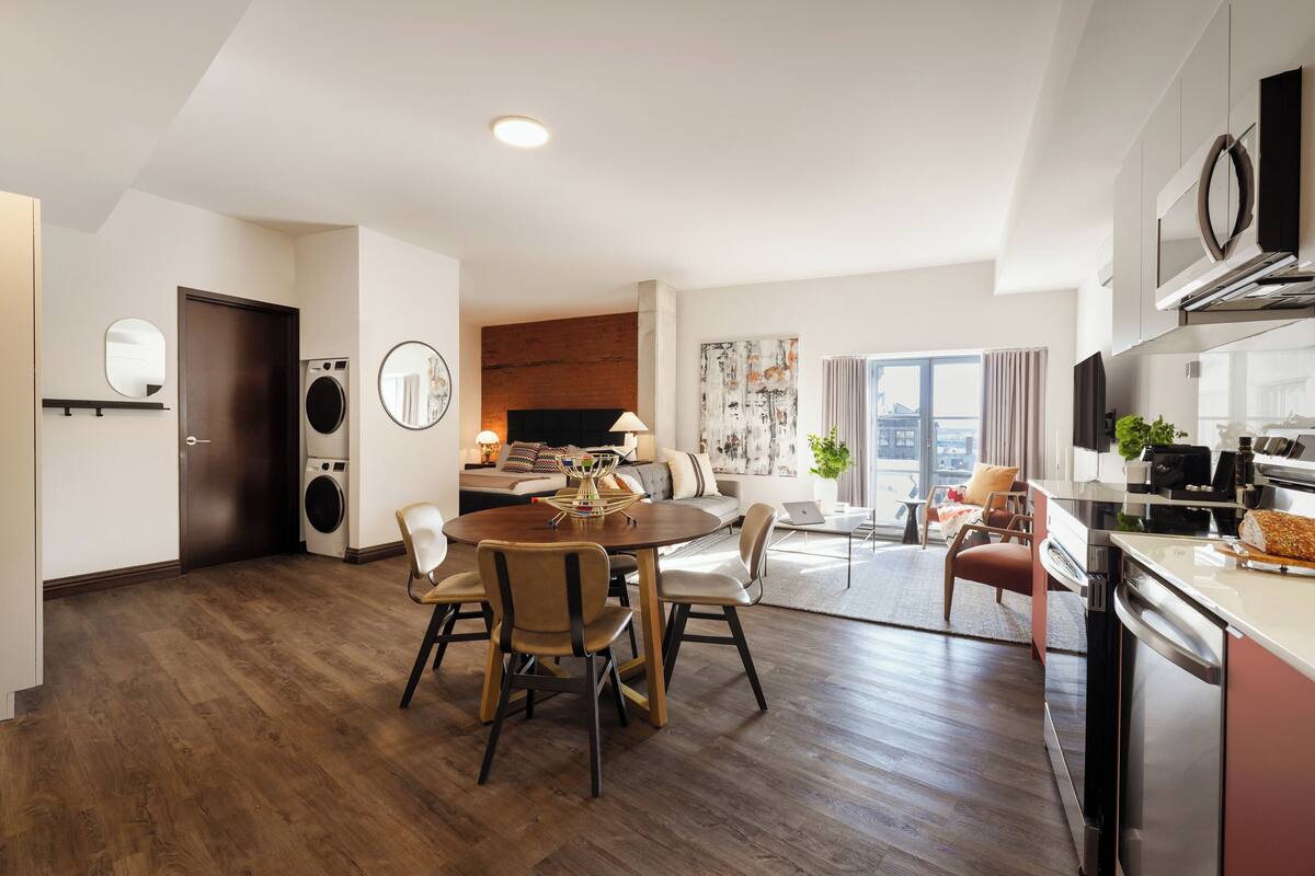 A modern apartment with a dining area, kitchen, and laundry room.