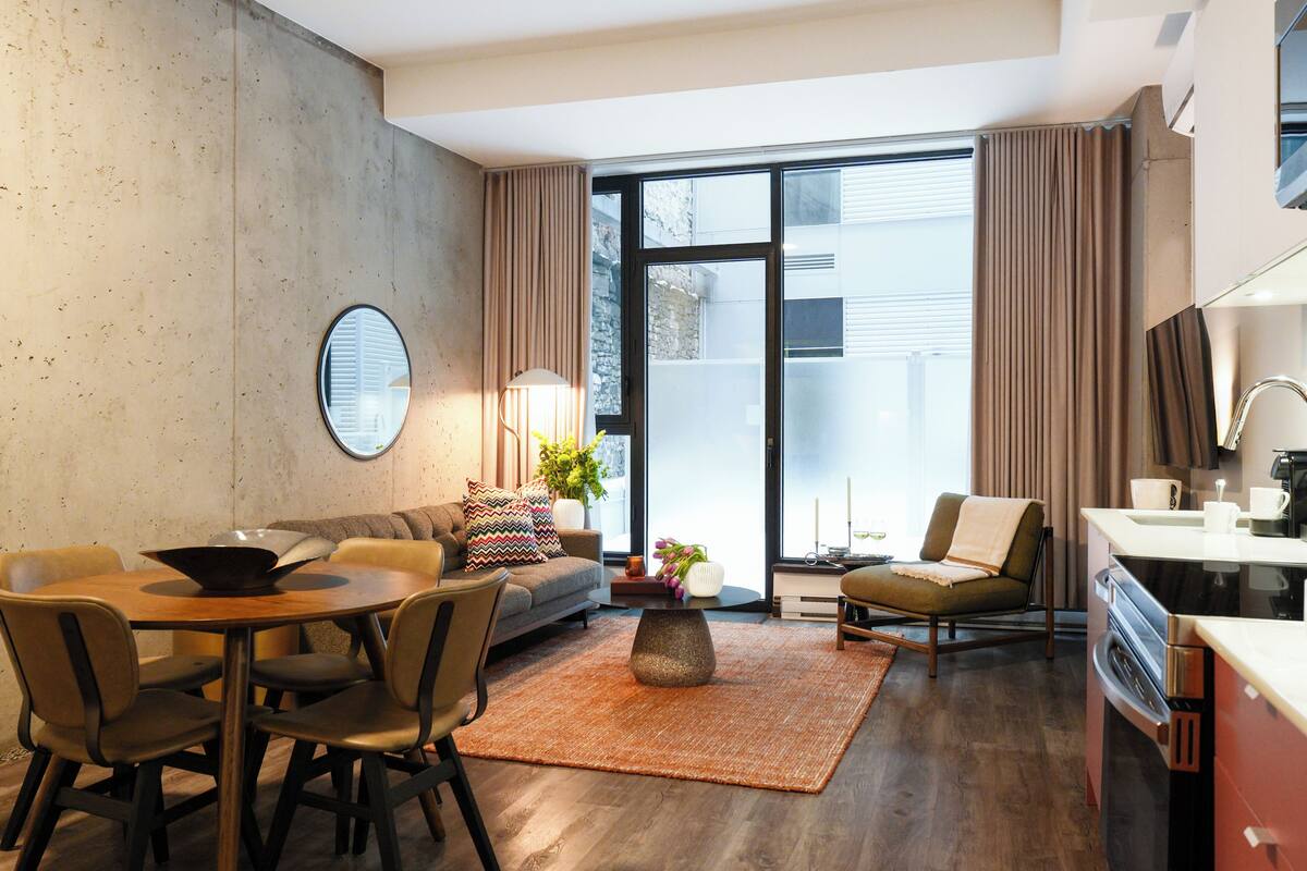 A modern living room with a dining area, a sofa, a coffee table, and a kitchen area with a stove.