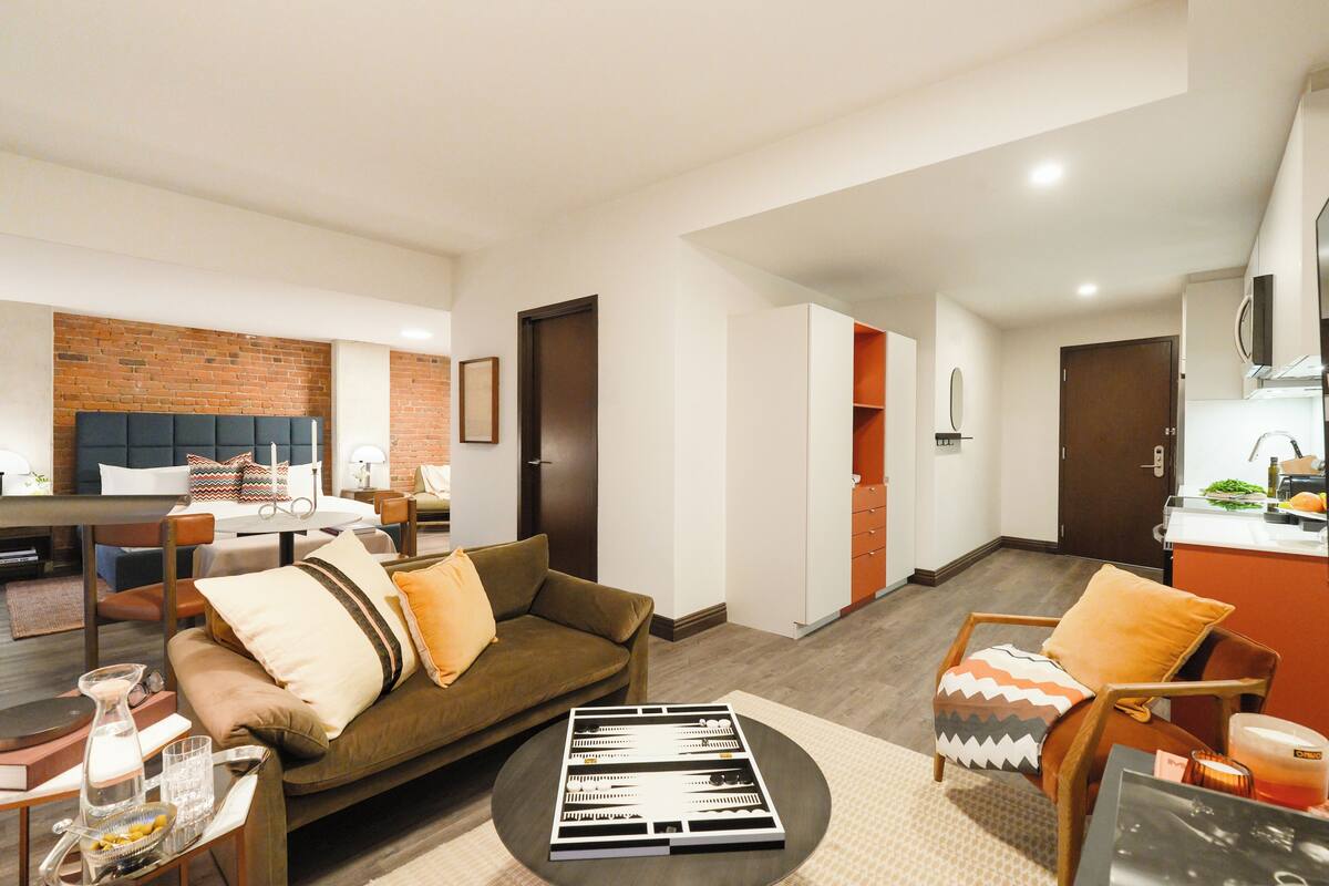 A modern living room with a sofa, coffee table, and a dining area with a table and chairs.