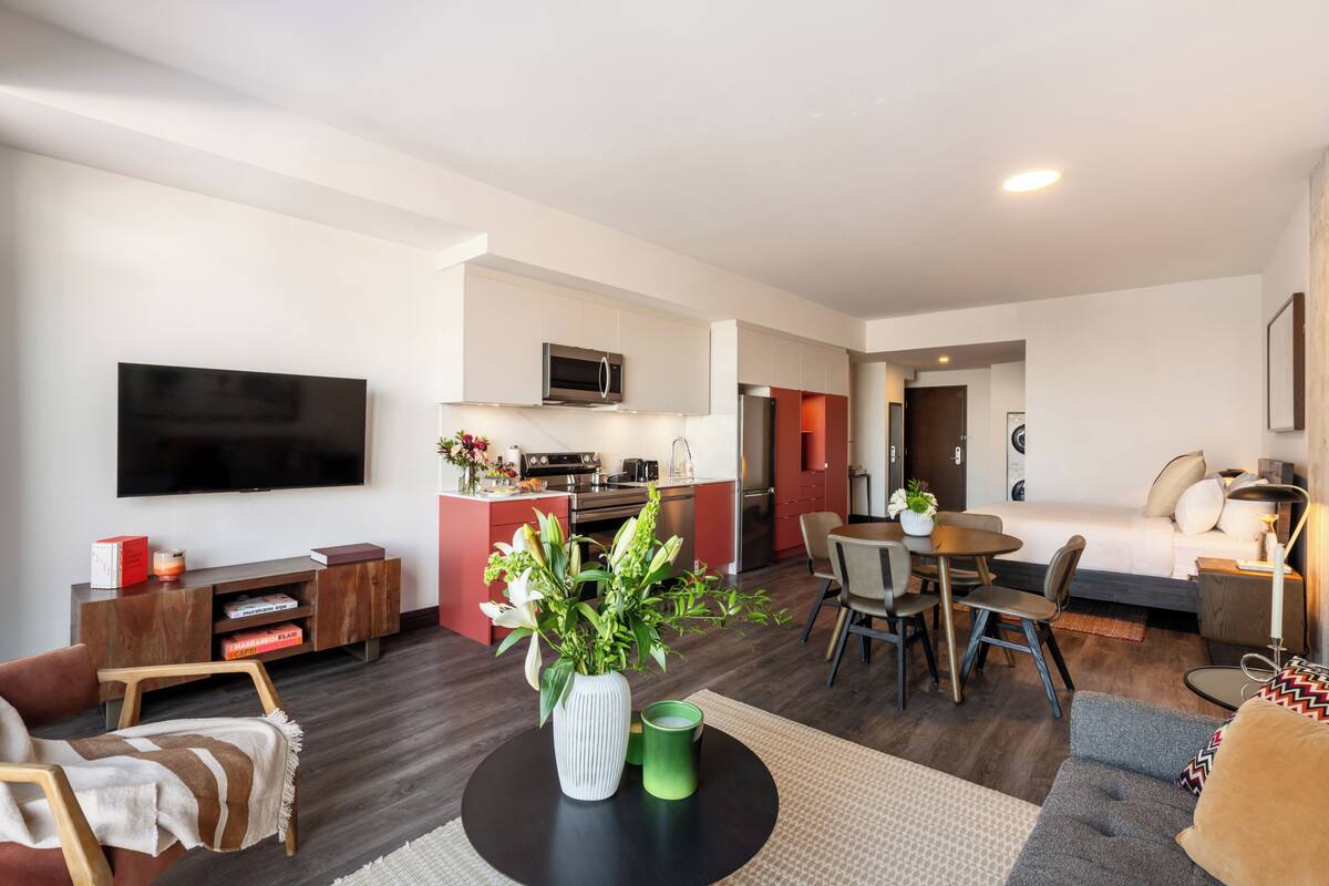 A modern apartment with a living room, dining area, kitchenette, and a bedroom.