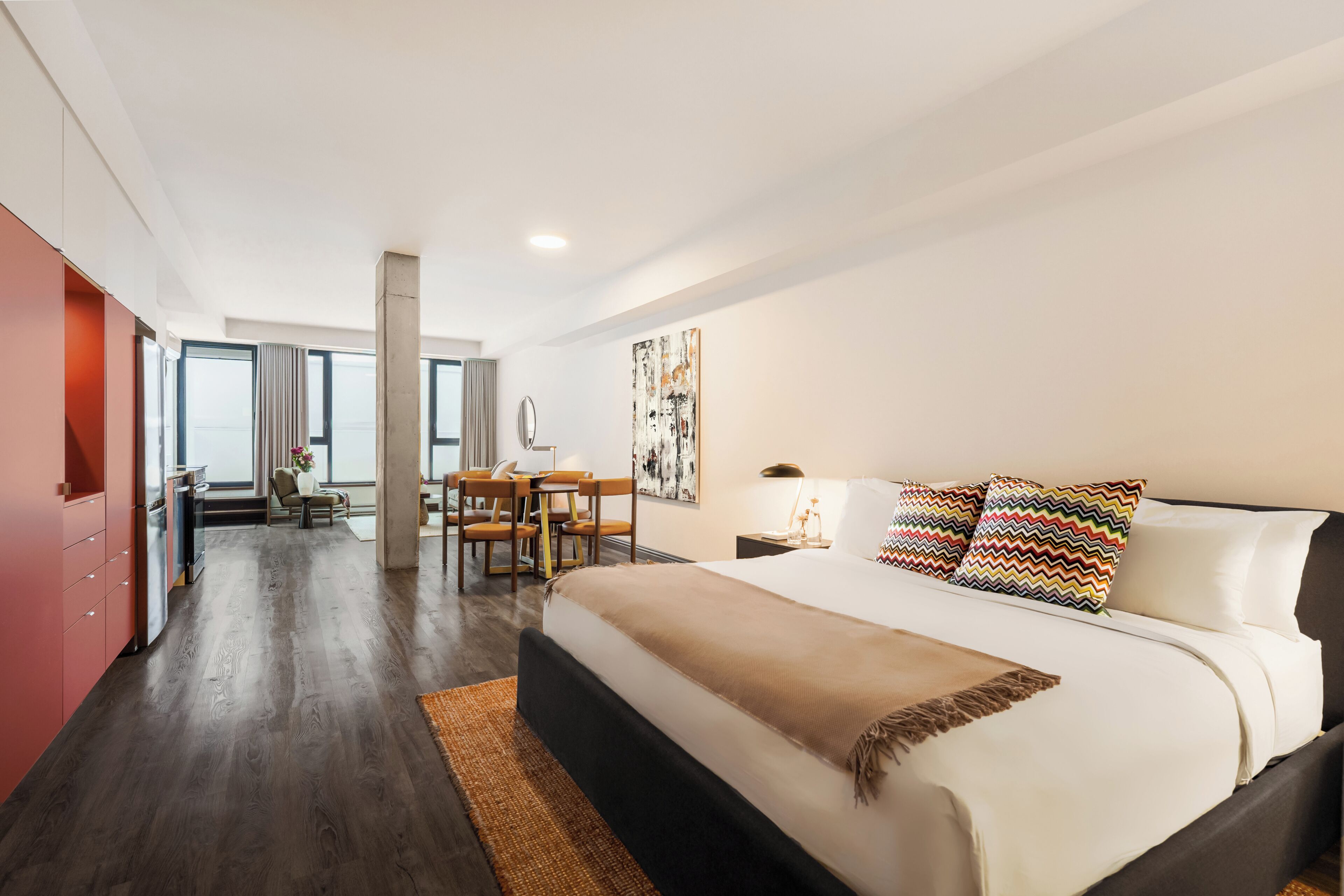 A modern hotel room with a large bed, a desk, and a view through the window.