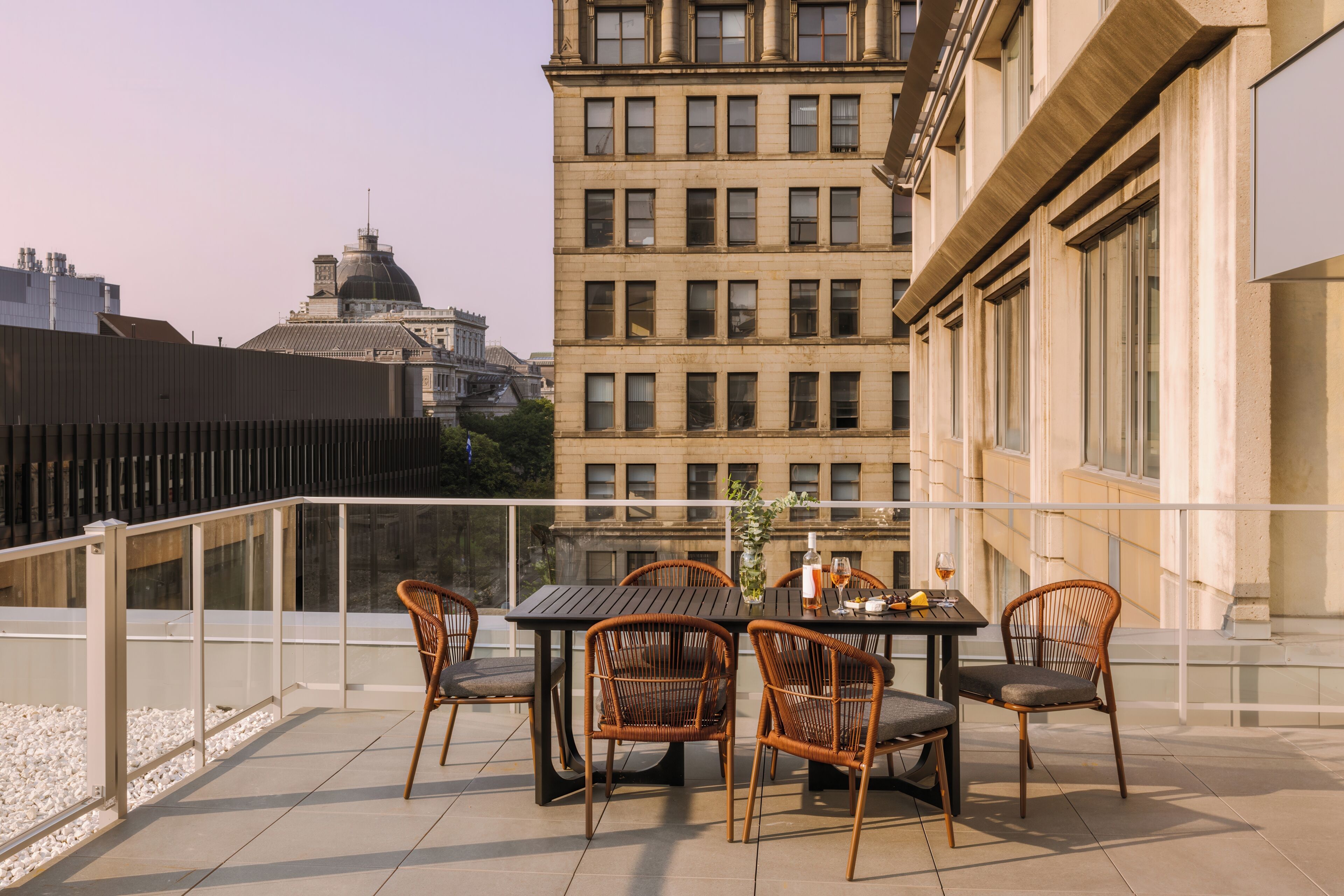 A terrace with a table and chairs, overlooking a cityscape with historic buildings.