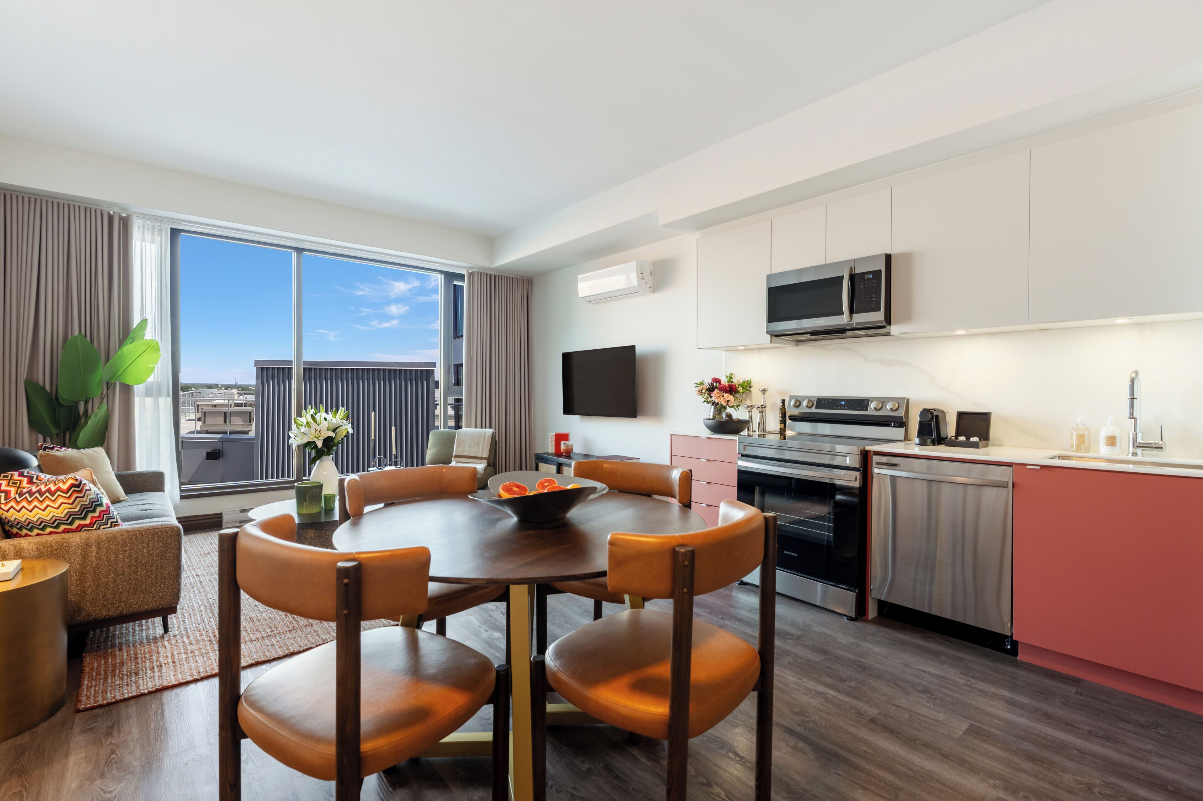 Habitación de hotel moderna con comedor, cocina y un amplio ventanal con vistas a la ciudad.