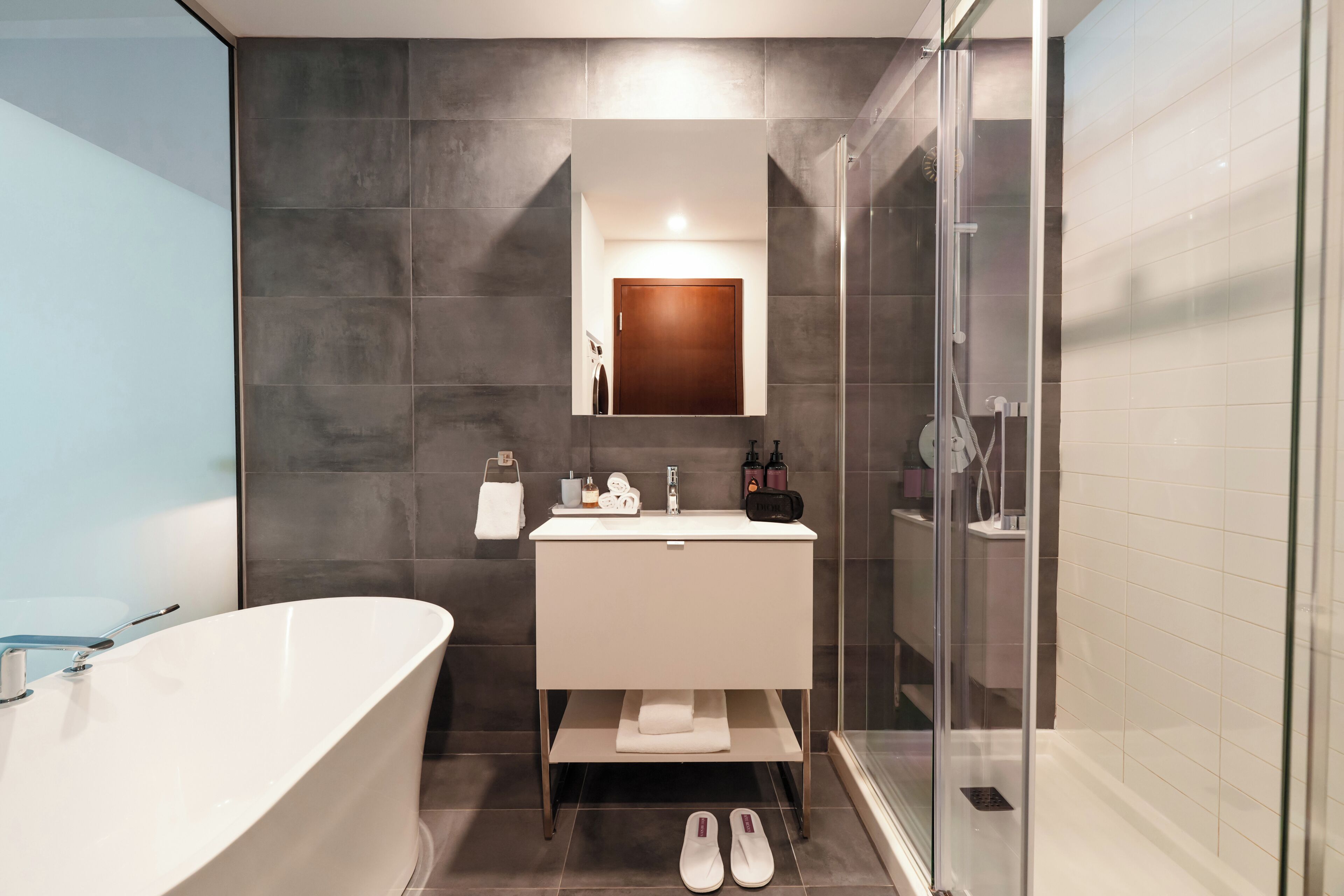 Une salle de bain moderne avec une baignoire sur pieds, une douche à parois de verre et un meuble-lavabo avec un miroir au-dessus.