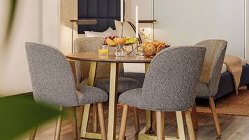 A dining area with a table set for four, chairs, a candle, and a fruit bowl.