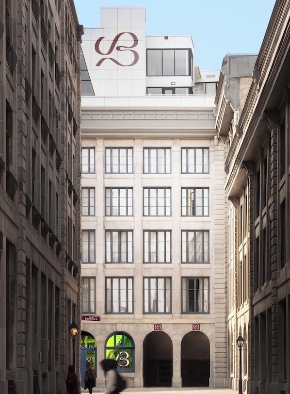 A building with a large, prominent logo on the facade, multiple windows, and a central entrance with three arches. - Brésoles Hotel (Montréal)