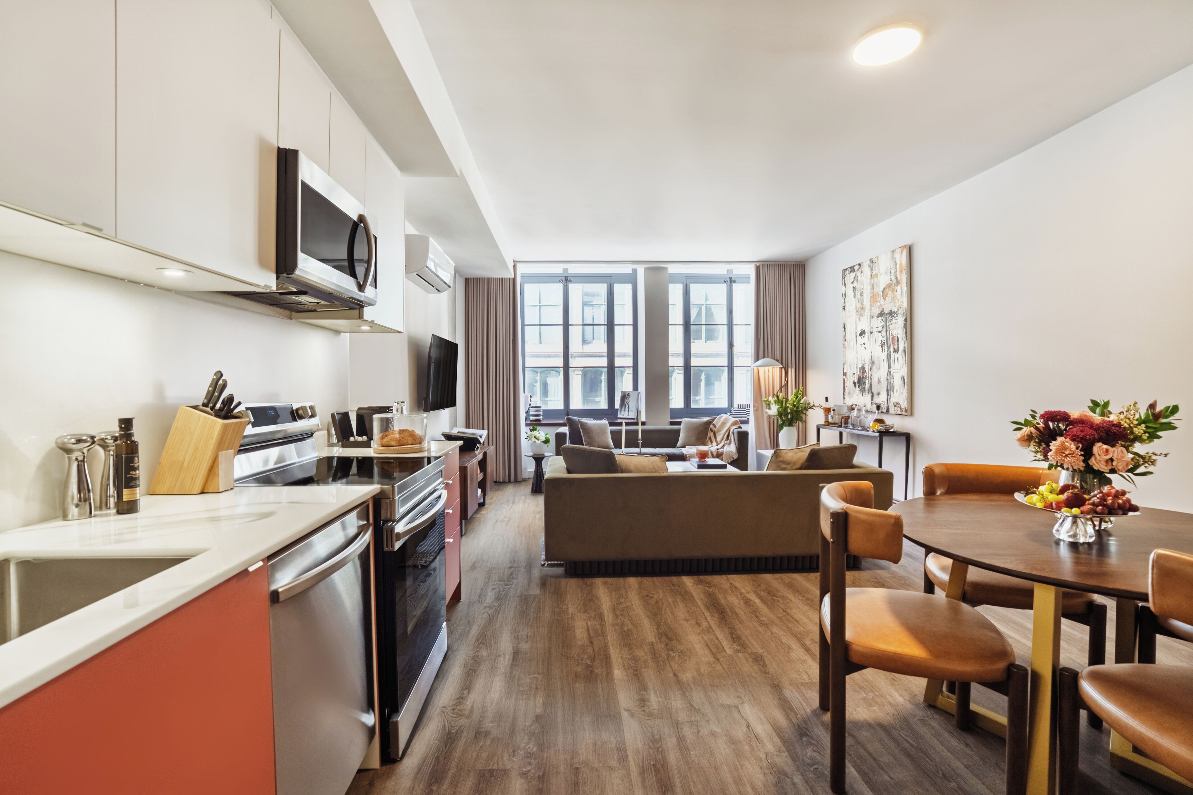 A modern kitchen with a microwave, oven, and sink, a dining area with a table and chairs, and a living area with a sofa and a coffee table.
