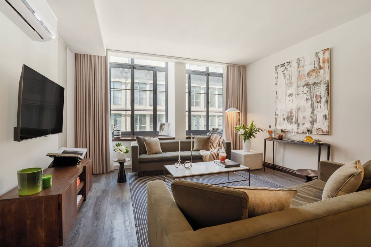 A modern living room with a sofa, coffee table, TV, and artwork.