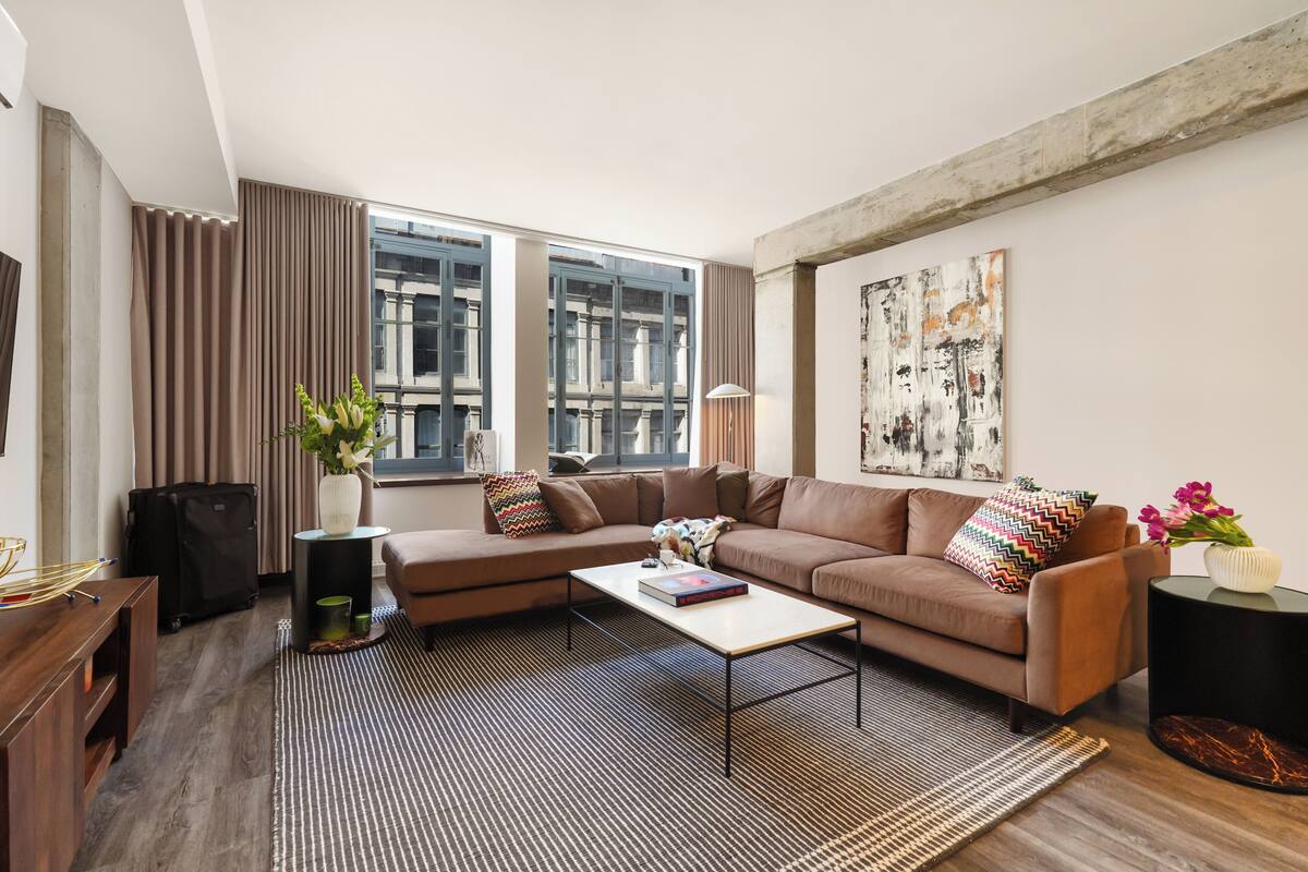 A modern living room with a sectional sofa, a coffee table, and a large window with curtains.