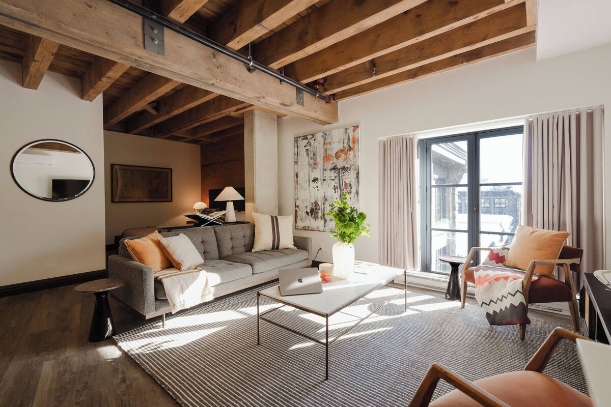 A modern living room with a sofa, coffee table, and a large window with curtains.