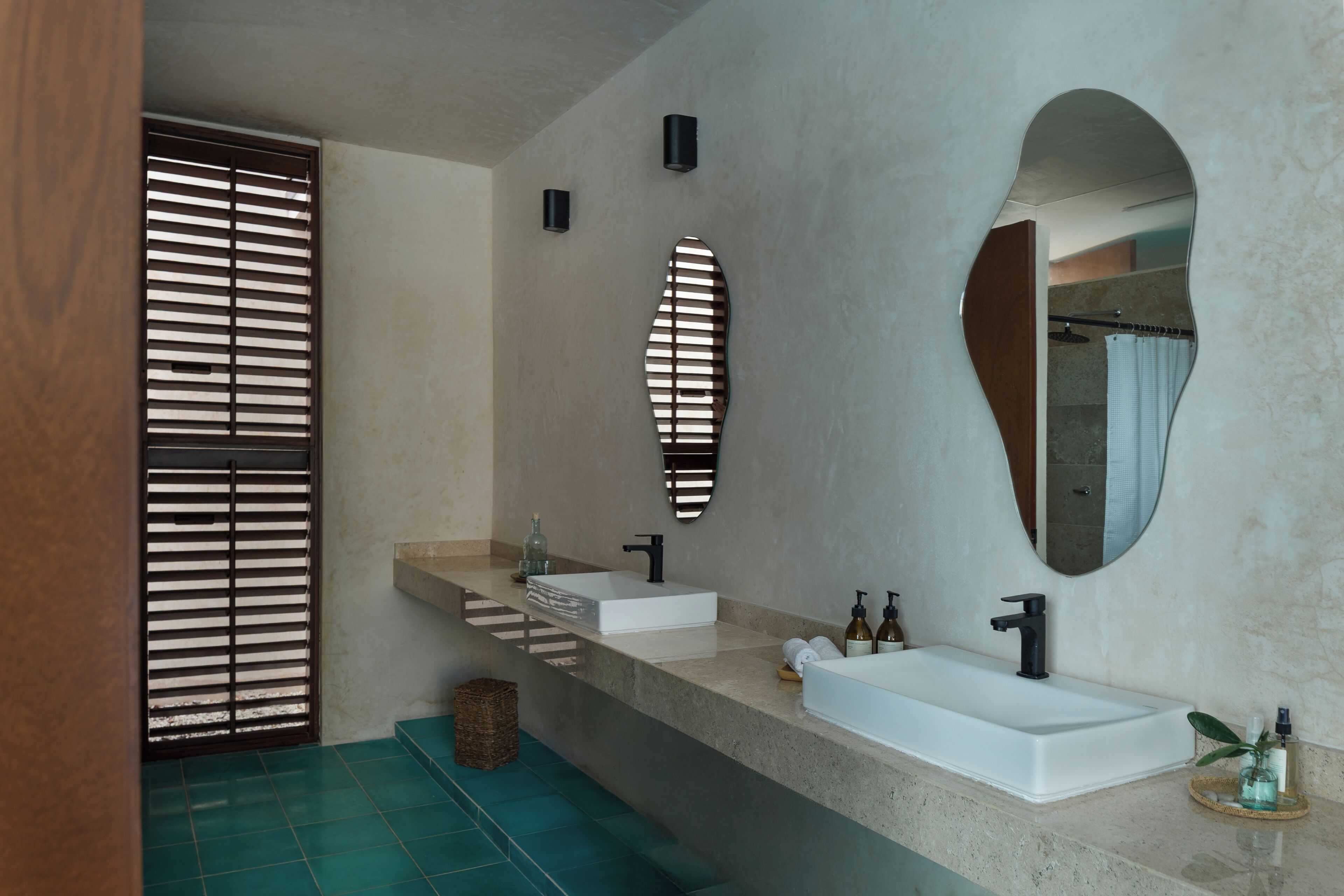 A modern bathroom with a large mirror, two sinks, and a shower area.