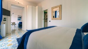 A bedroom with a bed, a mirror, and a view into the dining area. - Elegant Apartment for 4 in Chiaia - Capri View Terrace (Napoli)