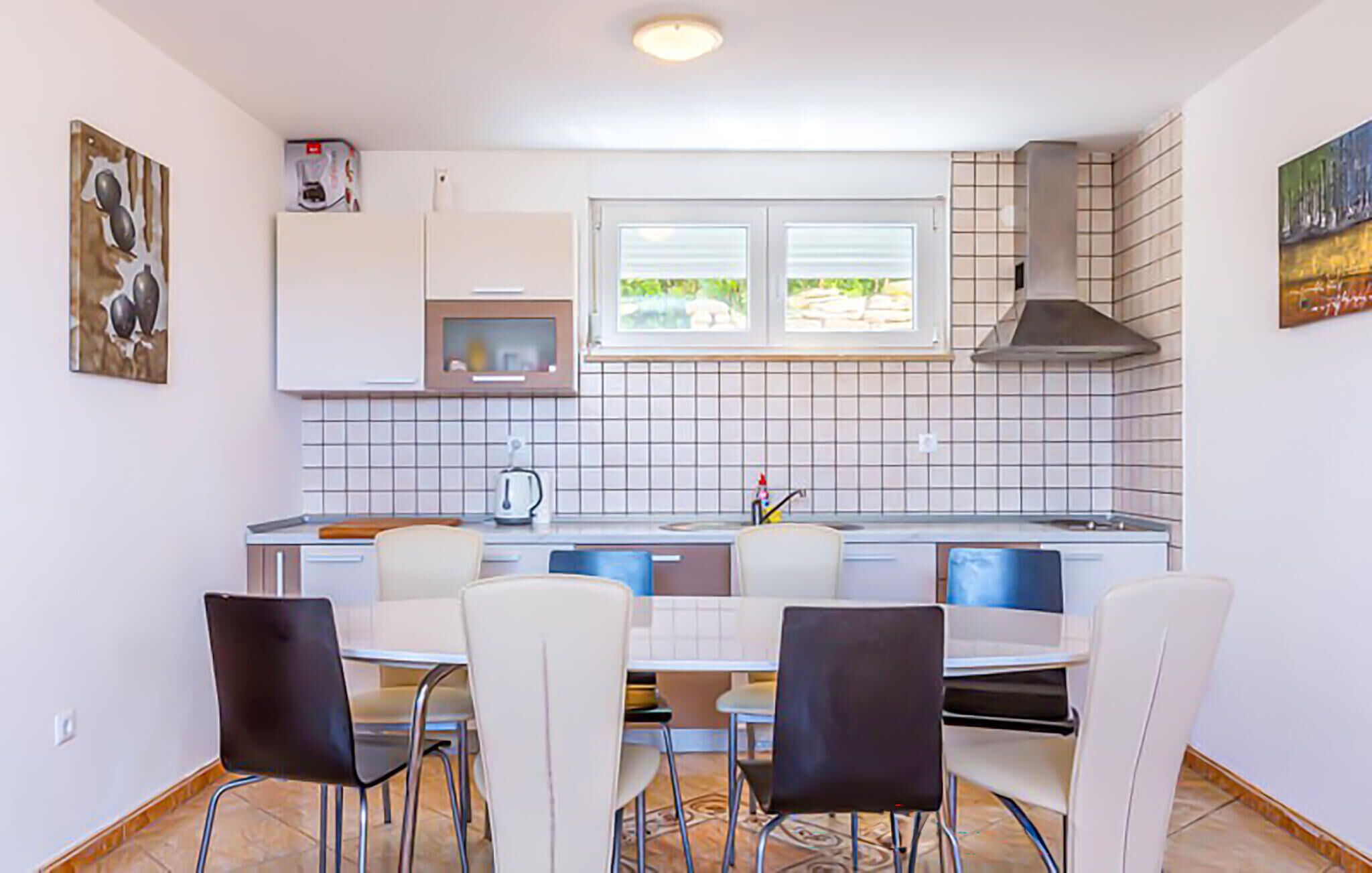 A compact kitchen with a dining area, white cabinets, a microwave, a stove, and a window with a view of greenery.