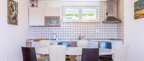 A compact kitchen with a dining area, white cabinets, a microwave, a stove, and a window with a view of greenery.