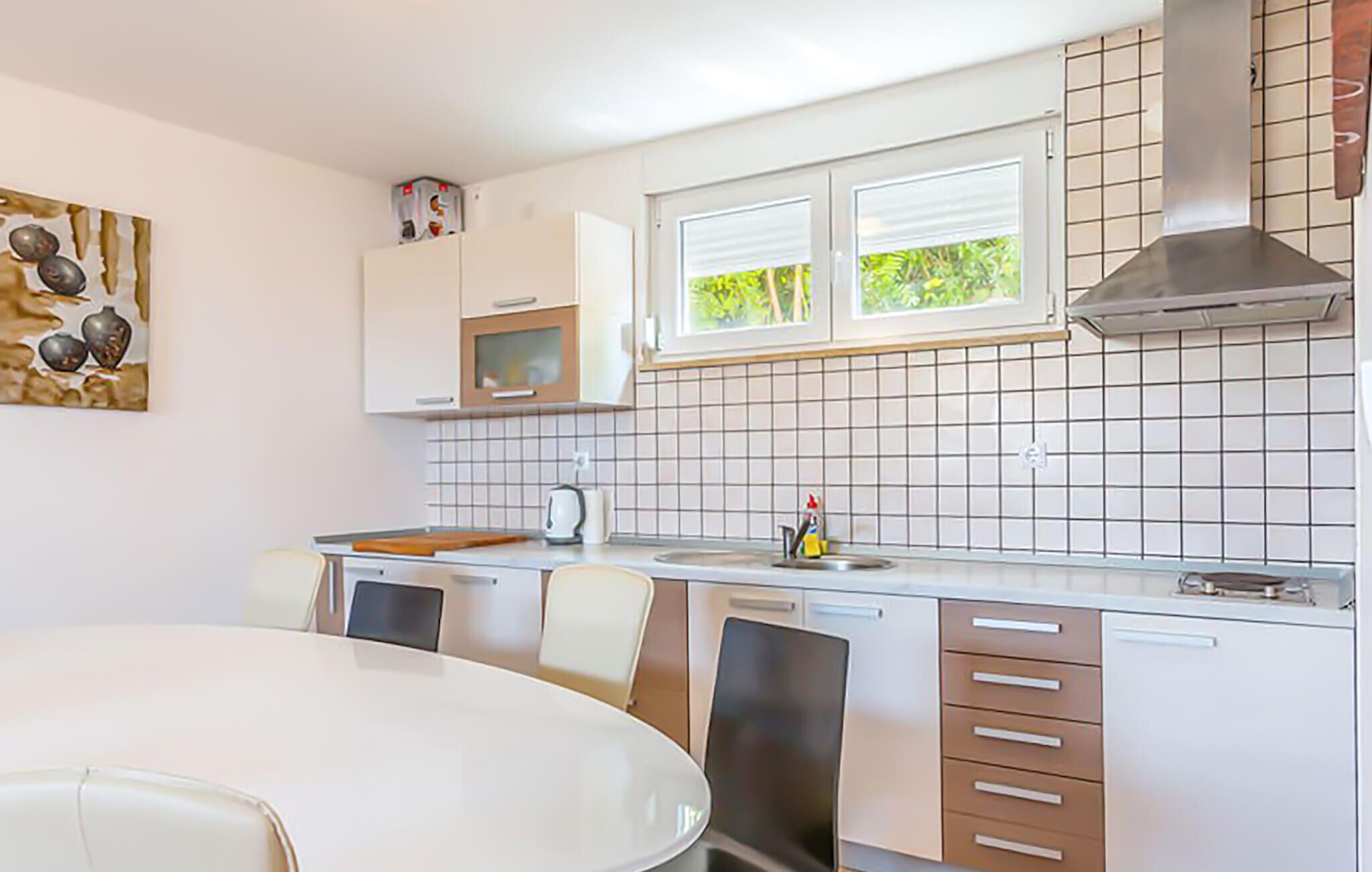 A modern kitchen with white cabinets, a microwave, a stove, and a window with blinds.