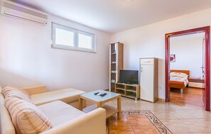 A compact hotel room with a sofa, a small table, a TV, a wardrobe, and a bed with a red frame. - 2 bedroom lovely apartment in Medulin (Medulin)