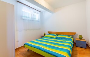 A bedroom with a bed, a nightstand, a drawer unit, a window with curtains, and a door. - 2 bedroom cozy apartment in Medulin (Medulin)