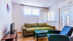 A living room with a sofa, a coffee table, a TV, and a door with a window. - 2 bedroom cozy apartment in Medulin (Medulin)