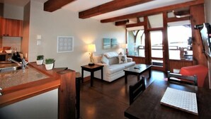 A kitchen with a sink, countertop, and cabinets, a dining area with a table and chairs, a sofa, and a lamp. - Seaside Ucluelet Hotel (Ucluelet)