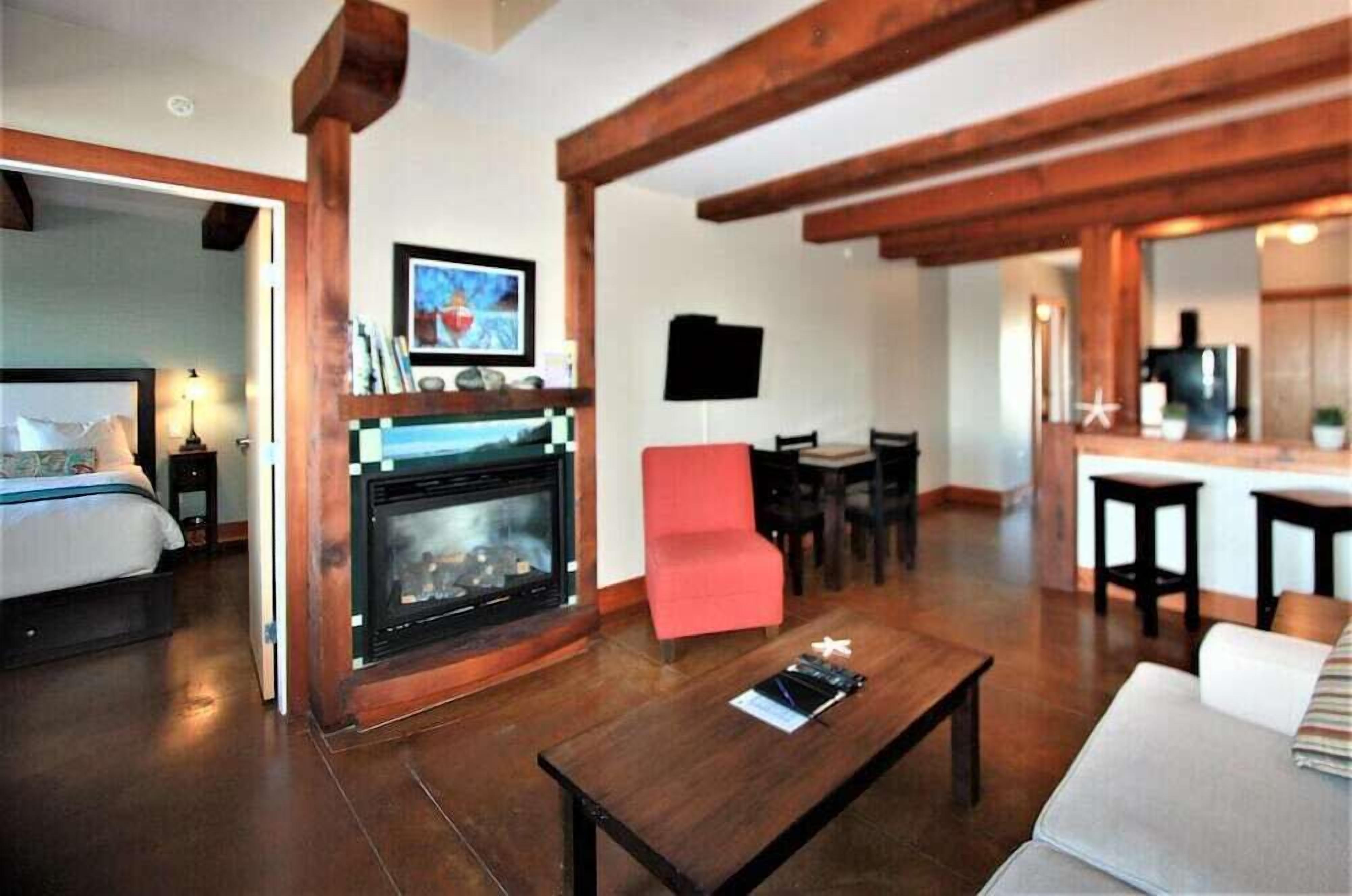 A room with a fireplace, a red chair, a dining area, and a bed.