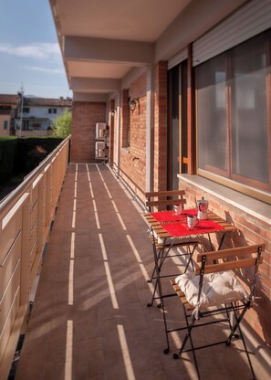 A balcony with a table and chairs, a window, and a door. - Il Posto Giusto in Lucca: Short-Term Rentals in Italy (Lucca)