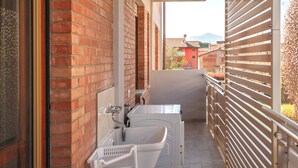 Ein schmaler Balkon mit einer Ziegelwand, einer weißen Badewanne und einem Metallgeländer.