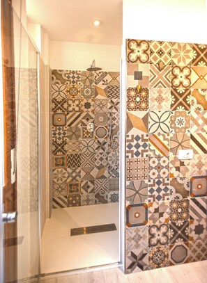 A bathroom with a shower, tiled walls with various patterns, and a glass door. - Il Posto Giusto in Lucca: Short-Term Rentals in Italy (Lucca)