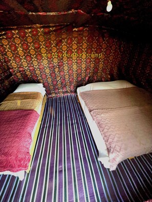Una habitación con dos camas, papel tapiz estampado y colcha a rayas.