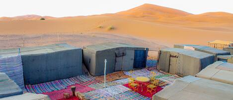 A desert camp with tents, colorful rugs, and a drum set.
