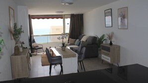 Un salon moderne avec un canapé, une table à manger, des chaises et une vue sur la mer.