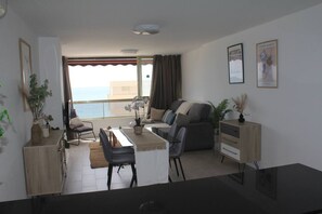 Ein modernes Wohnzimmer mit einer Couch, einem Esstisch, Stühlen und Meerblick.