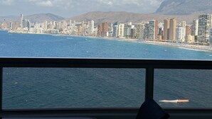 A coastal cityscape with high-rise buildings, a beach, and mountains in the background.
