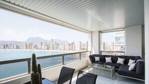 A balcony with a city view, a sofa, a dining table, and a cactus.