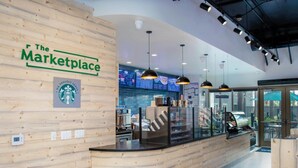 A wooden reception desk with a Starbucks logo, overhead lighting, and a digital menu board in the background. - Family sized 2 BR, 2 Bath, 6 guest resort condo 5 minutes to Disneyland (Anaheim)