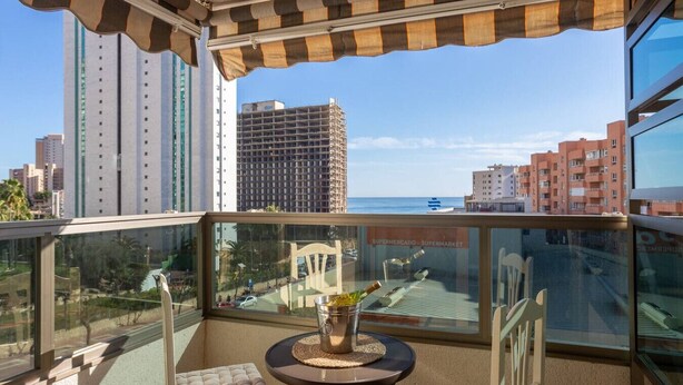 A balcony with a view of the cityscape and the sea, a small table with a bottle, and a cushioned chair. - Apto 4 pax  a 2 minutos playa.A/C,terraza.Piscina. (La Vila Joiosa)