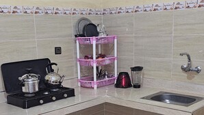 A kitchen with a gas stove, a pink storage rack, a blender, and a sink. - Campsite. Where you are you going to spend your nights in desert. (Merzouga)