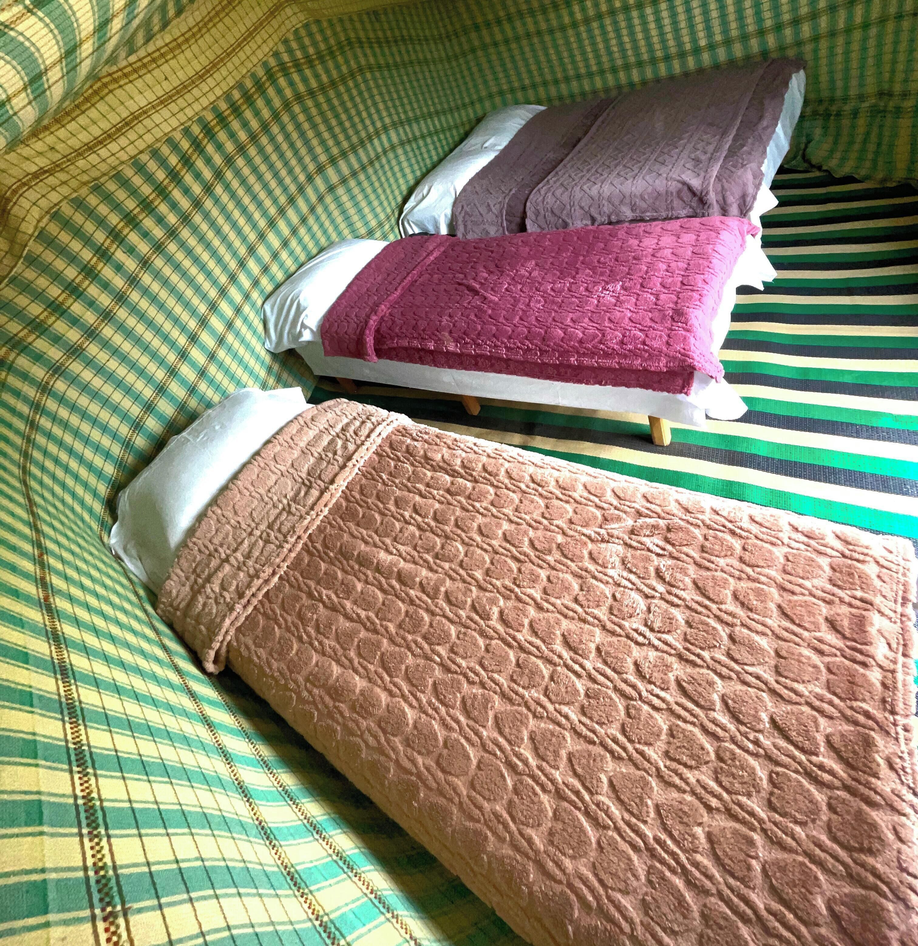 A bed with a checkered blanket, pillows, and a striped bedspread.